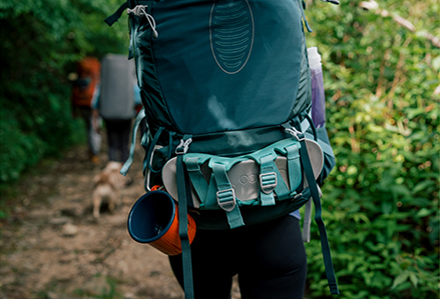 Close up of a backpack on a female's back, with a pair of Chaco Chillos strapped to the outside.