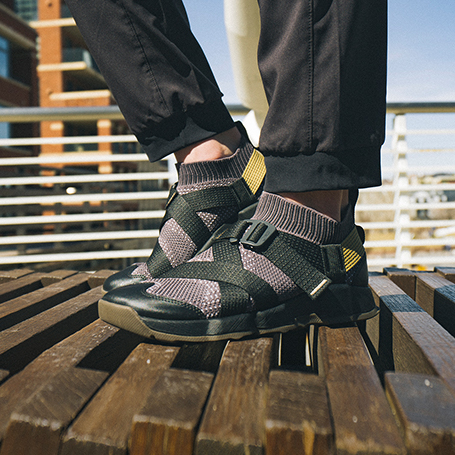 Person standing on a dock wearing black Chaco shoes