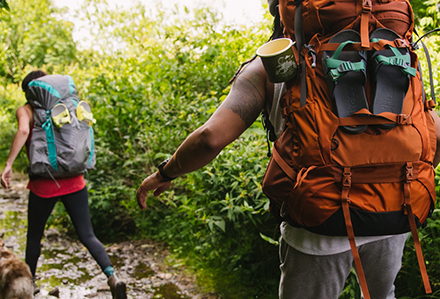 Close up of a backpack on a male's back, with a pair of Chaco Chillos strapped to the outside.