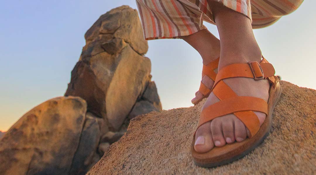Person on a rock, sporting Chaco Women's Wayfarer sandals.