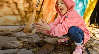 Kid playing outside on rocks wearing Chaco sandals
