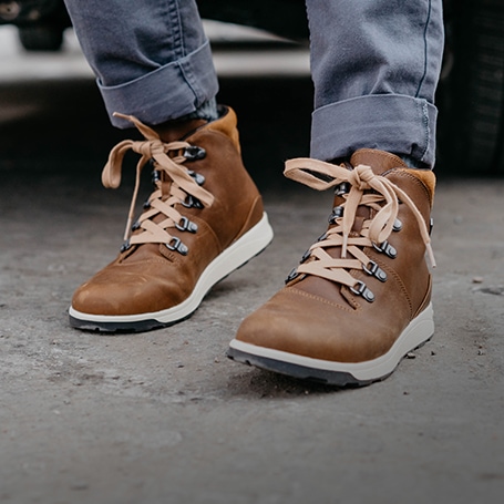 Person standing next to a car, wearing brown Chaco boots