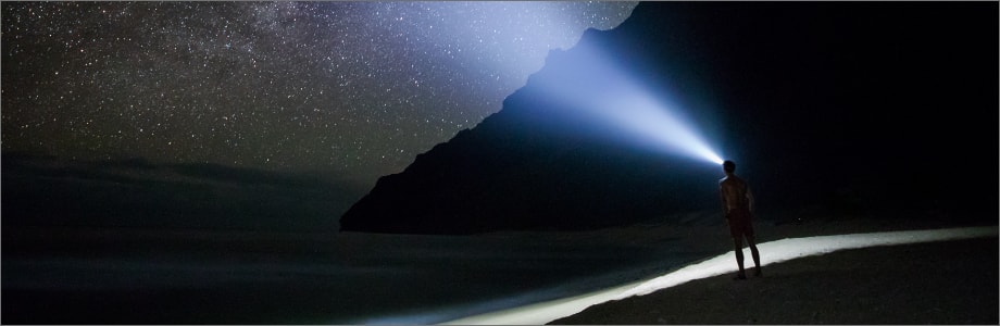 Person in the dark by a mountain, looking at the stars