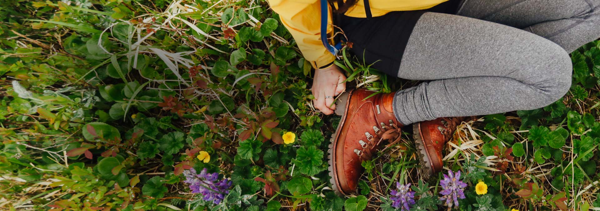 Brown waterproof boots on a woman sitting in a field.