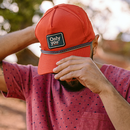 Person putting on an orange Chaco hat