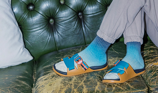 Person holding up purple Z-Sandals in front of leaves.